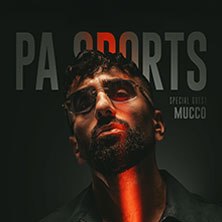 Mann mit Sonnenbrille und Bart, rotes Licht auf Gesicht, dunkler Hintergrund mit 'PA Sports' und 'Mucco' Schriftzug., © links im Bild