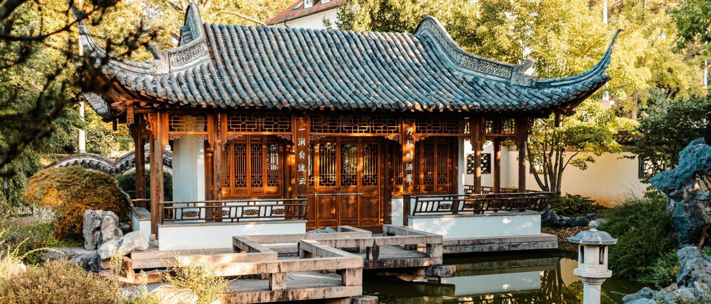 Traditionelles chinesisches Gebäude im Chinesischen Garten Stuttgart, umgeben von Bäumen und einem Teich., © Stuttgart-Marketing GmbH, Sarah Schmid
