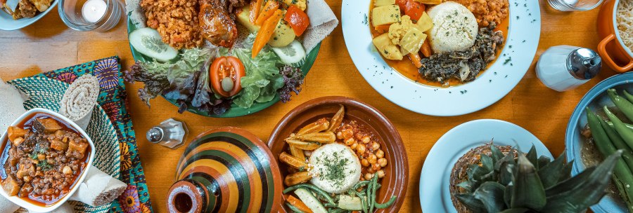 Ein Tisch mit eritreischen Gerichten, darunter Injera, Gem&uuml;se und Eint&ouml;pfe. Bunte Teller und Schalen mit verschiedenen Speisen., &copy; Dennis Winter Photography