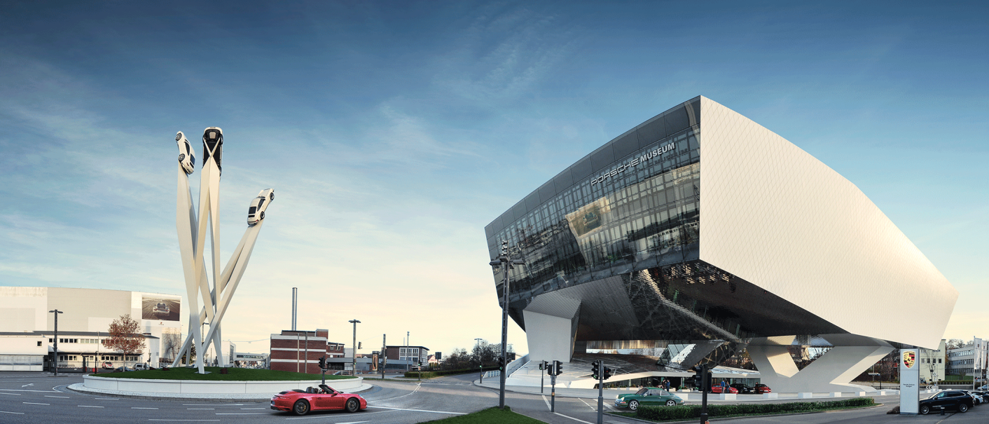 The Porsche Museum in Stuttgart with its futuristic architecture and a sculpture of three cars on tall pillars against a blue sky., © Porsche AG
