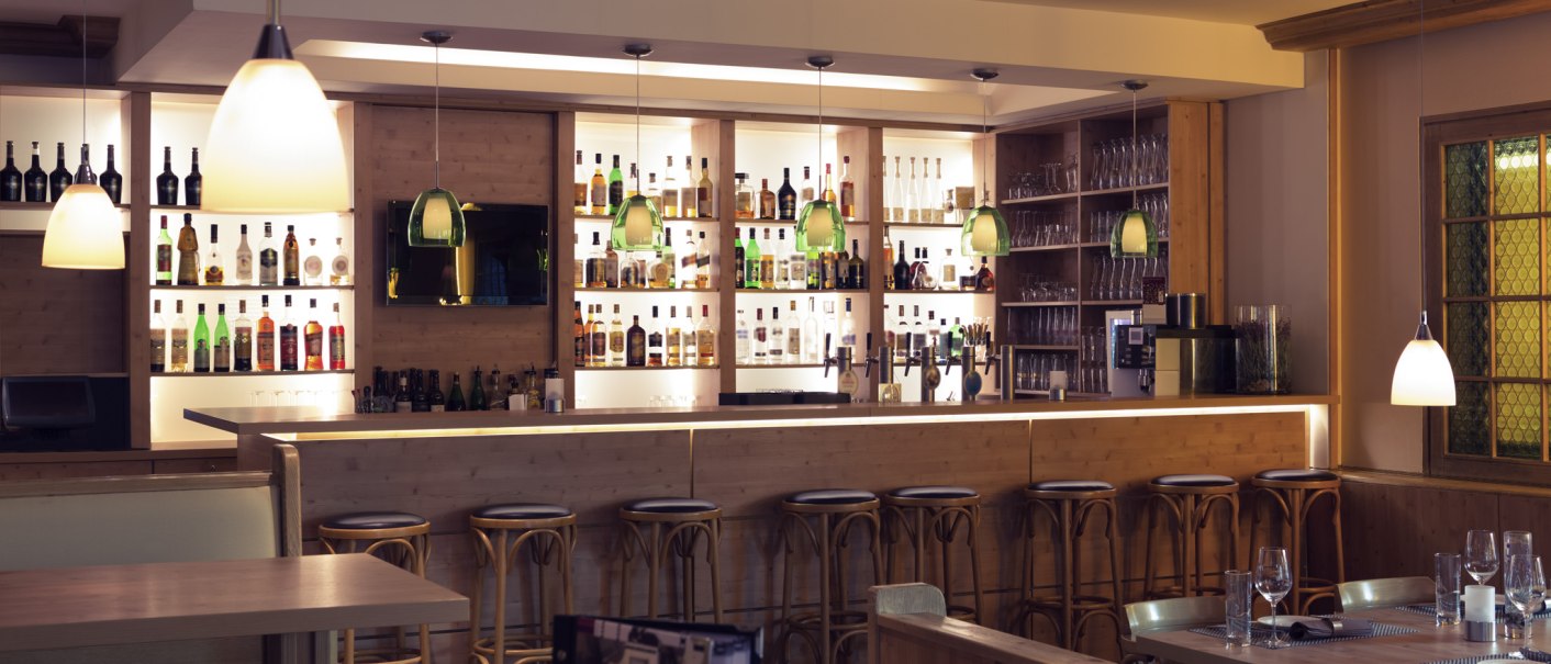 Stilvolle Bar mit Holztheke, Barhockern und beleuchteten Regalen voller Flaschen. Hängelampen und gedeckte Tische schaffen eine gemütliche Atmosphäre., © Mercure Hotel Stuttgart Sindelfingen an der Messe Stilvolle Bar mit Holztheke, Barhockern und beleuchteten Regalen voller Flaschen. Hängelampen und gedeckte Tische schaffen eine gemütliche Atmosphäre., © Mercure Hotel Stuttgart Sindelfingen an der Messe