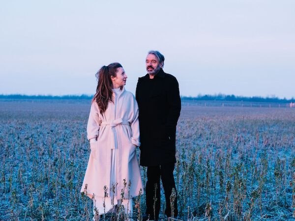 Zwei Personen in Wintermänteln stehen in einem frostigen Feld bei Sonnenuntergang. Der Himmel ist pastellfarben, die Landschaft wirkt ruhig und kalt., © Theaterhaus Stuttgart e.V. Zwei Personen in Wintermänteln stehen in einem frostigen Feld bei Sonnenuntergang. Der Himmel ist pastellfarben, die Landschaft wirkt ruhig und kalt., © Theaterhaus Stuttgart e.V.