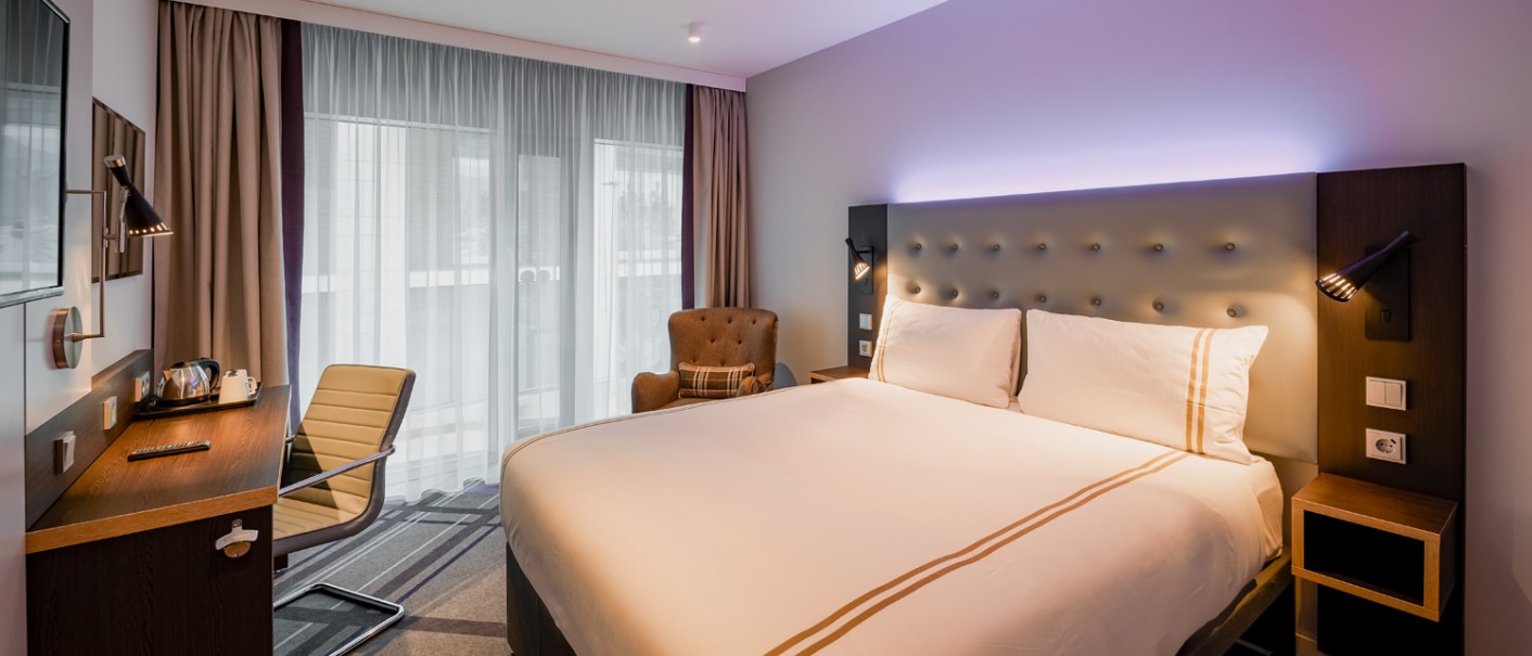 Modernes Doppelzimmer mit großem Bett, Schreibtisch, Sessel und Fenster mit Vorhängen. Dezente Beleuchtung und stilvolle Einrichtung., © Premier Inn Modernes Doppelzimmer mit großem Bett, Schreibtisch, Sessel und Fenster mit Vorhängen. Dezente Beleuchtung und stilvolle Einrichtung., © Premier Inn