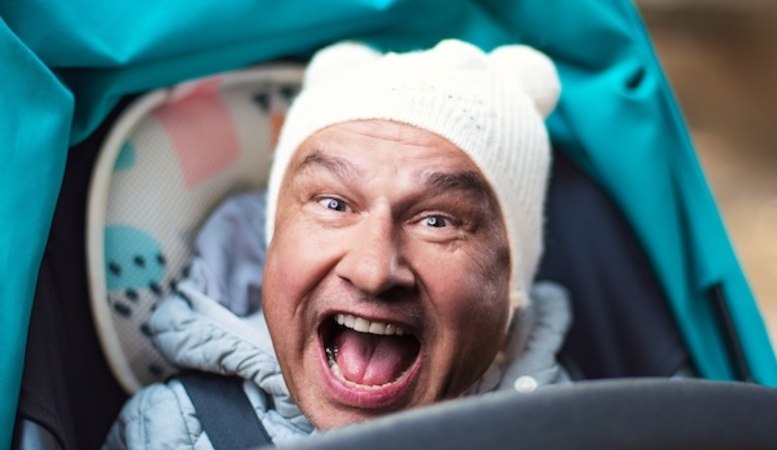 Ein Mann mit weißer Mütze sitzt in einem Kinderwagen und lacht fröhlich. Der Hintergrund ist unscharf., © Renitenztheater Stuttgart e.V. Ein Mann mit weißer Mütze sitzt in einem Kinderwagen und lacht fröhlich. Der Hintergrund ist unscharf., © Renitenztheater Stuttgart e.V.