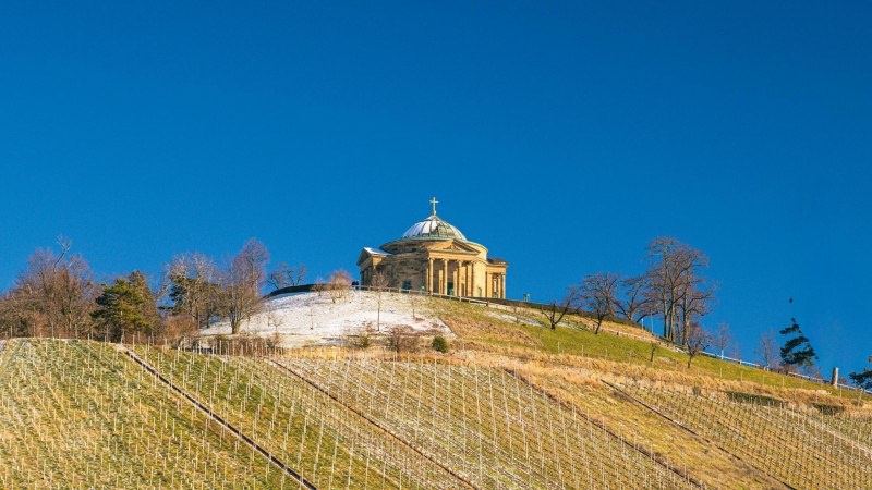 The burial chapel on Württemberg is enthroned on a snow-covered hill, surrounded by vineyards under a clear blue sky., © Stuttgart-Marketing GmbH, Sarah Schmid The burial chapel on Württemberg is enthroned on a snow-covered hill, surrounded by vineyards under a clear blue sky., © Stuttgart-Marketing GmbH, Sarah Schmid