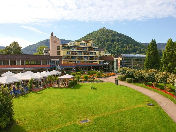 Das Hotel Graf Eberhard von der Parkseite aus gesehen, mit gepflegtem Garten und einem bewaldeten Hügel im Hintergrund., © ©hotel-graf-eberhard.de