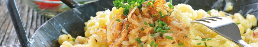 Cheese spaetzle with fried onions and chives in a pan, served with a fresh salad of tomatoes and cucumber., © kab-vision - Fotolia