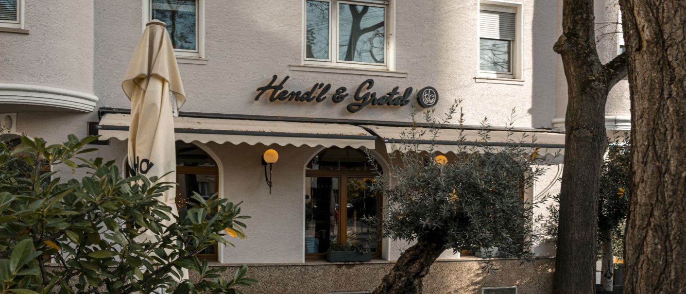 The picture shows the fa&ccedil;ade of the Hendl & Gretel restaurant with a parasol and plants in the foreground., &copy; SMG Stuttgart Marketing GmbH - Sarah Schmid