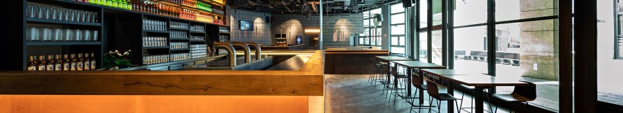 Modern caf&eacute; with bar, illuminated shelves full of bottles, glasses and seating areas. Large windows let in plenty of light., &copy; Maks Richter