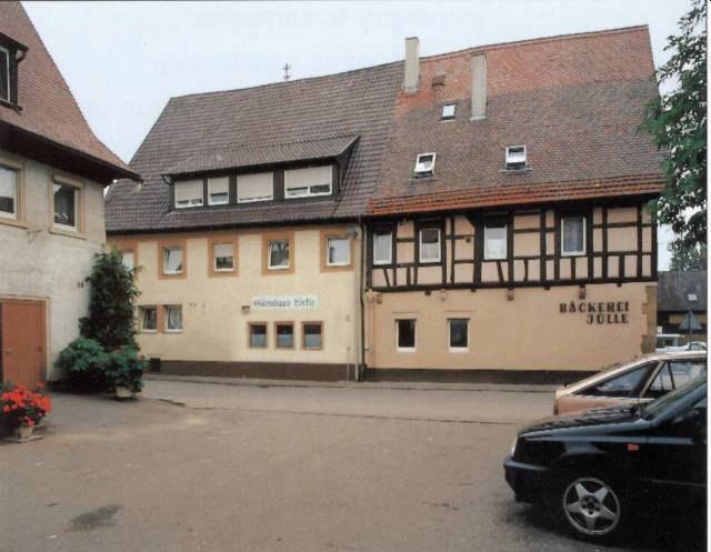 Fachwerkhaus mit Bäckerei Jülle und Gästehaus Löckle in Remseck-Neckargröningen. Vor dem Gebäude stehen Autos und Pflanzen., © Gästehaus Löckle