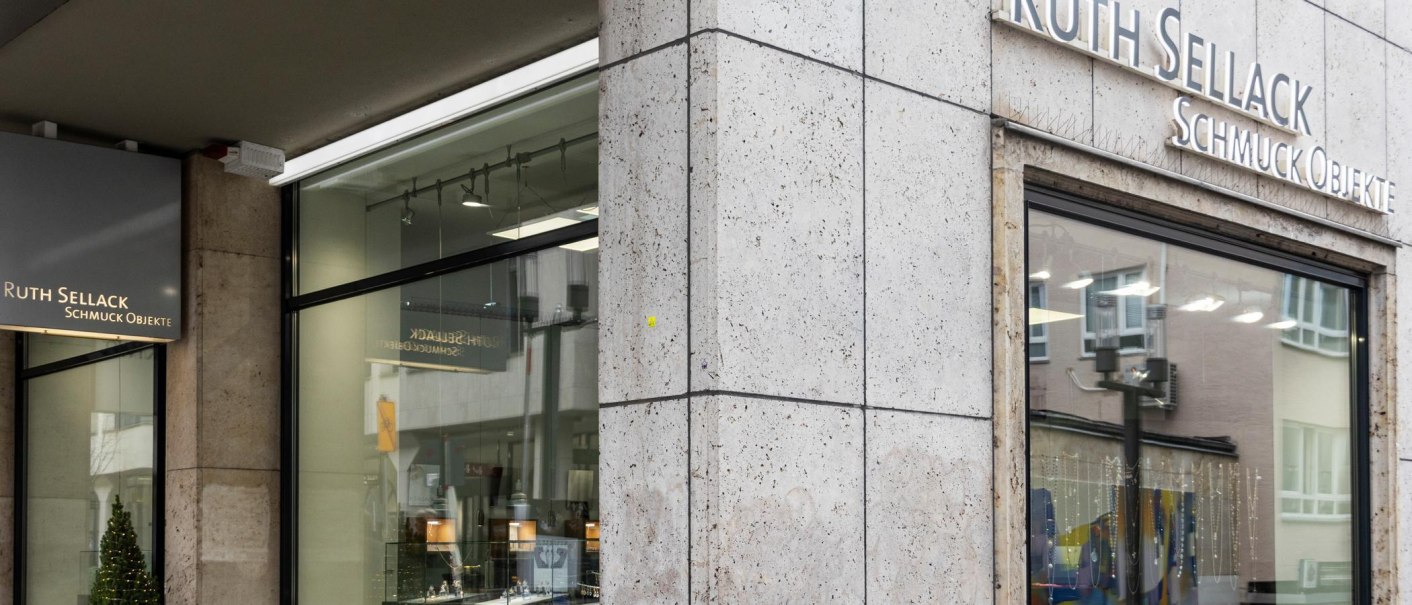 An illuminated sign with the inscription 'Ruth Sellack Schmuck Objekte' hangs on the wall of a stone building., © SMG, Sarah Schmid An illuminated sign with the inscription 'Ruth Sellack Schmuck Objekte' hangs on the wall of a stone building., © SMG, Sarah Schmid