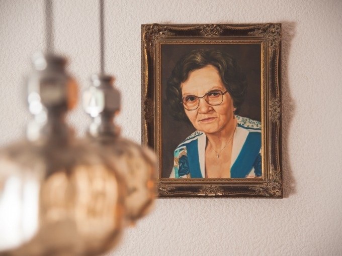 A painting of an elderly woman in an ornate frame hangs on a wall. Blurred lamps can be seen in the foreground., &copy; ExitGames Stuttgart