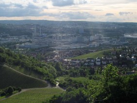 Panoramablick auf Untertürkheim: Weinberge im Vordergrund, Stadt und Industriegebäude im Hintergrund unter bewölktem Himmel., © Stuttgart-Marketing GmbH