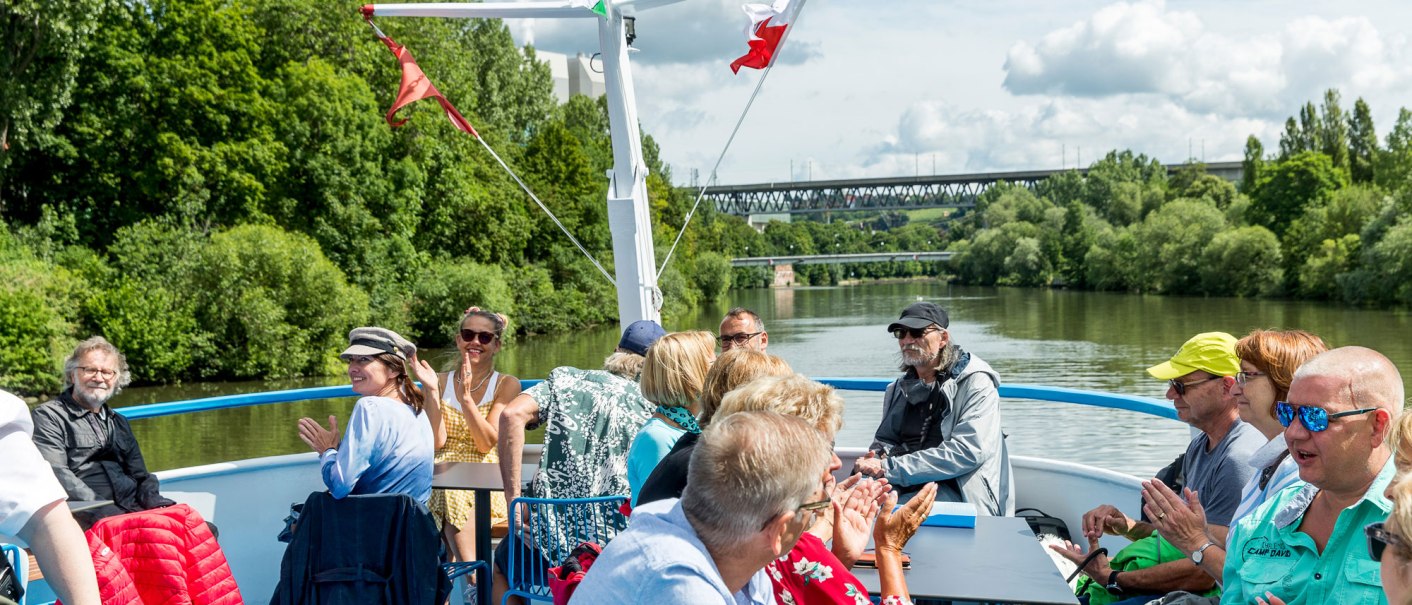 People enjoying a boat trip on the Neckar. They are sitting on the deck, surrounded by green countryside and chatting happily., © all copyrights are reserved by maks richter People enjoying a boat trip on the Neckar. They are sitting on the deck, surrounded by green countryside and chatting happily., © all copyrights are reserved by maks richter
