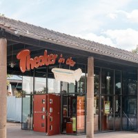 Eingang des Theaters in der Badewanne mit Glasfront und rotem Auto davor. Ein Schild mit dem Theaternamen und einer Badewanne ist sichtbar., &copy; Stuttgart Marketing GmbH, Sarah Schmid