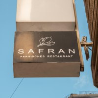 Sign of a Persian restaurant called Safran on a house wall, against a blue sky., &copy; SMG Stuttgart Marketing GmbH - Sarah Schmid