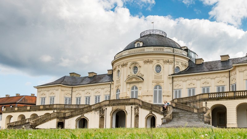 Solitude Palace with baroque architecture, staircase and green meadow in the foreground. The sky is cloudy., © Kartin Lehr VIEL UNTERWEGS Solitude Palace with baroque architecture, staircase and green meadow in the foreground. The sky is cloudy., © Kartin Lehr VIEL UNTERWEGS