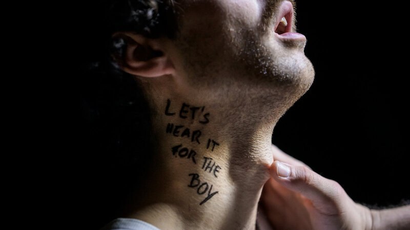 Nahaufnahme eines m&auml;nnlichen Halses mit der Aufschrift 'Let's hear it for the boy'. Eine Hand ber&uuml;hrt sanft den Hals., &copy; FITZ Das Theater animierter Formen