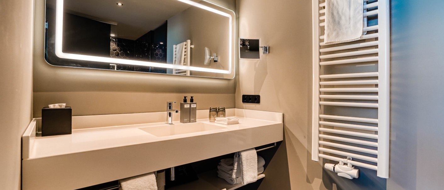 Modernes Badezimmer mit beleuchtetem Spiegel, Waschbecken und Handtuchhalter. Elegantes Design mit klaren Linien und neutralen Farben., © CLOUD N°7 APARTMENTS GmbH Modernes Badezimmer mit beleuchtetem Spiegel, Waschbecken und Handtuchhalter. Elegantes Design mit klaren Linien und neutralen Farben., © CLOUD N°7 APARTMENTS GmbH