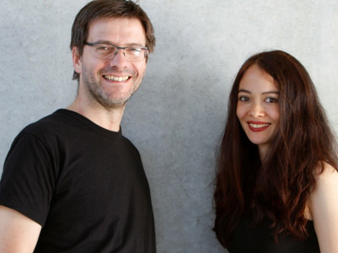 A man and a woman smile at the camera. The man is wearing glasses and a black T-shirt, the woman has long dark hair. The background is gray., &copy; Landesmuseum W&uuml;rttemberg