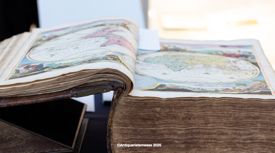 An old book with a colorful world map lies open on a table, presented at the Antiquarian Book Fair 2025., &copy; Antiquariatsmesse, 2025