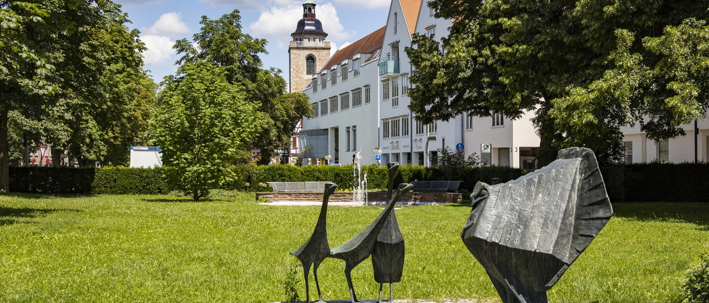 Green park landscape with modern sculptures in the foreground, a fountain and a church tower in the background in Kirchheim unter Teck., © Torsten Wenzler