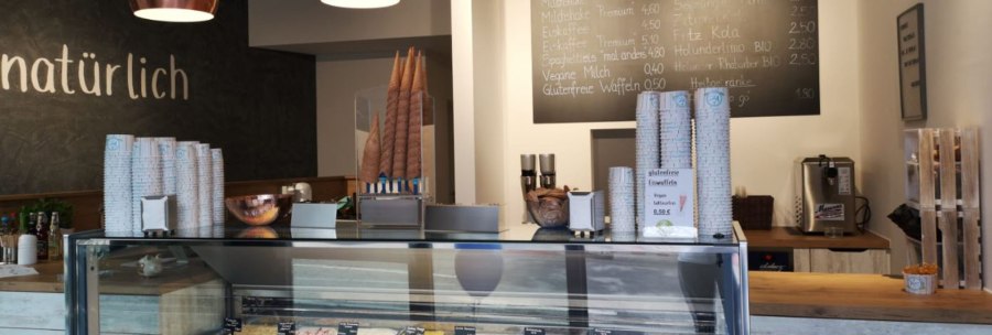 Ice cream parlor with ice cream counter, various types of ice cream, menu board and modern lighting. 'Naturally' lettering on the wall., &copy; Joannis Nakos