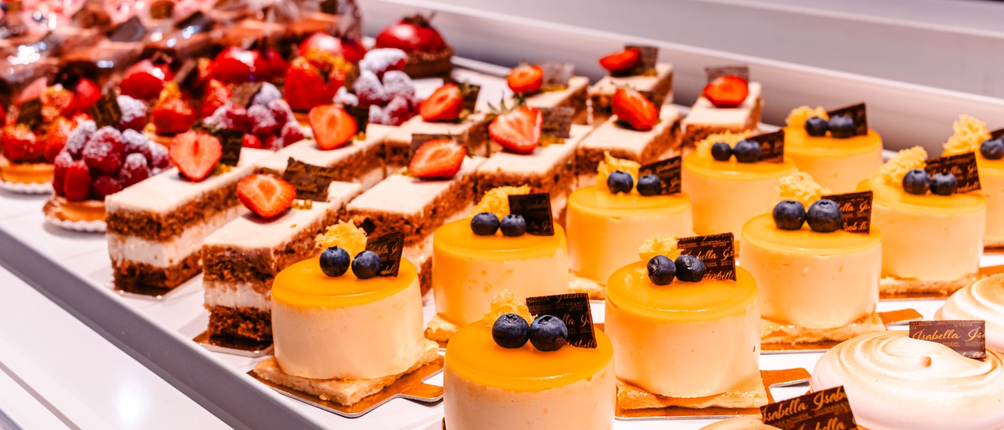 Vitrine mit verschiedenen Kuchen und Torten, darunter gelbe Törtchen mit Heidelbeeren und Erdbeerkuchen., © Sarah Schmid