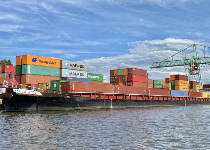 Ein Containerschiff im Stuttgarter Hafen mit bunten Containern und einem Kran im Hintergrund unter blauem Himmel., &copy; Stuttgart Marketing GmbH