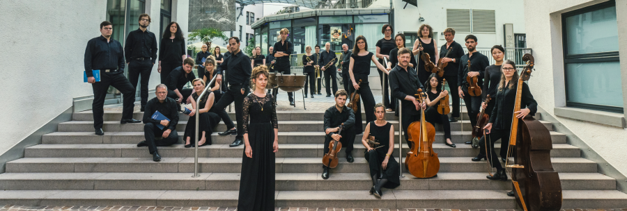 Eine Musikgruppe in schwarzer Kleidung posiert auf einer Treppe vor einem modernen Geb&auml;ude mit Glasdach., &copy; Martin F&ouml;rster
