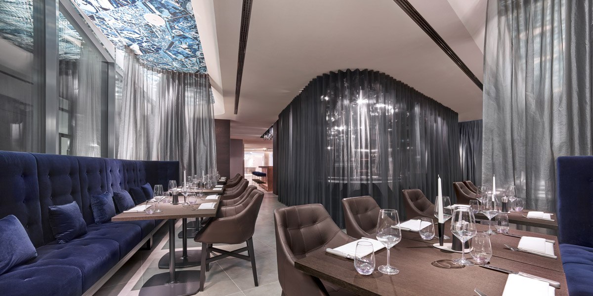 Elegant restaurant with blue benches, laid tables and modern curtains., © Jaz Hotel Stuttgart Elegant restaurant with blue benches, laid tables and modern curtains., © Jaz Hotel Stuttgart
