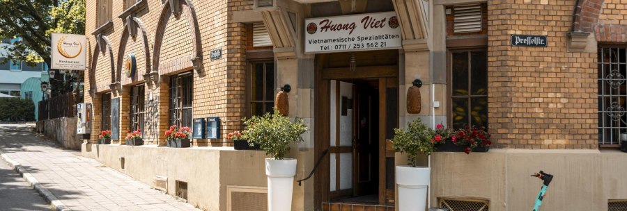 Eingang des Restaurants Huong Viet mit Blumenarrangements und einem E-Scooter auf dem Gehweg., © Stuttgart Marketing GmbH, Sarah Schmid Eingang des Restaurants Huong Viet mit Blumenarrangements und einem E-Scooter auf dem Gehweg., © Stuttgart Marketing GmbH, Sarah Schmid
