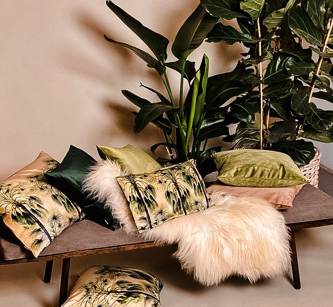 Ein Sofa mit bunten Kissen und einem weißen Fell, umgeben von großen grünen Zimmerpflanzen., © Merz & Benzing GmbH