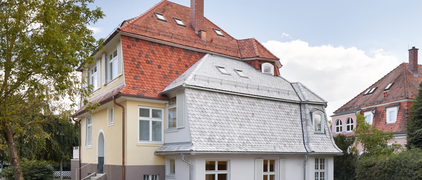 Zweist&ouml;ckiges Haus mit rotem Ziegeldach, gelber Fassade und wei&szlig;en Fenstern, umgeben von B&auml;umen und Rasen., &copy; Philip Kottlorz