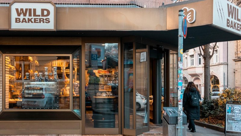 Fassade des Stores mit gro&szlig;en Schaufenstern. Durch die spiegelnden Scheiben erkennt man Backware in der Auslage., &copy; Stuttgart-Marketing GmbH, Sarah Schmid