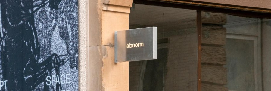 A metal sign with the words 'abnormal' hangs on a wall. Next to it is an art poster., &copy; SMG, Sarah Schmid