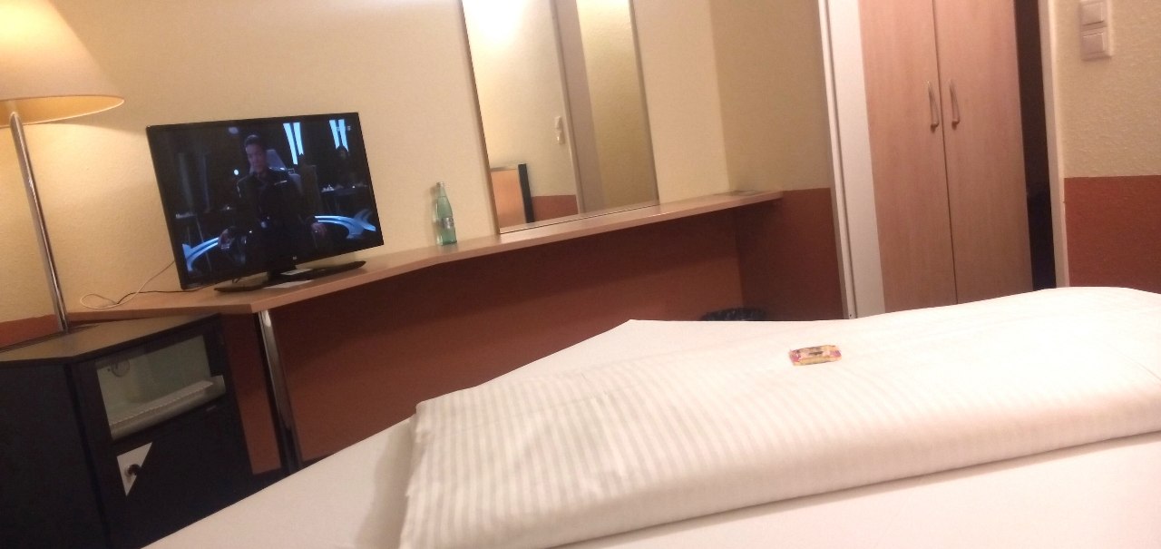 Ein gem&uuml;tliches Hotelzimmer mit einem Einzelbett, einem Fernseher, einem Spiegel und einem Kleiderschrank. Eine Lampe steht neben dem Fernseher., &copy; Central Hotel