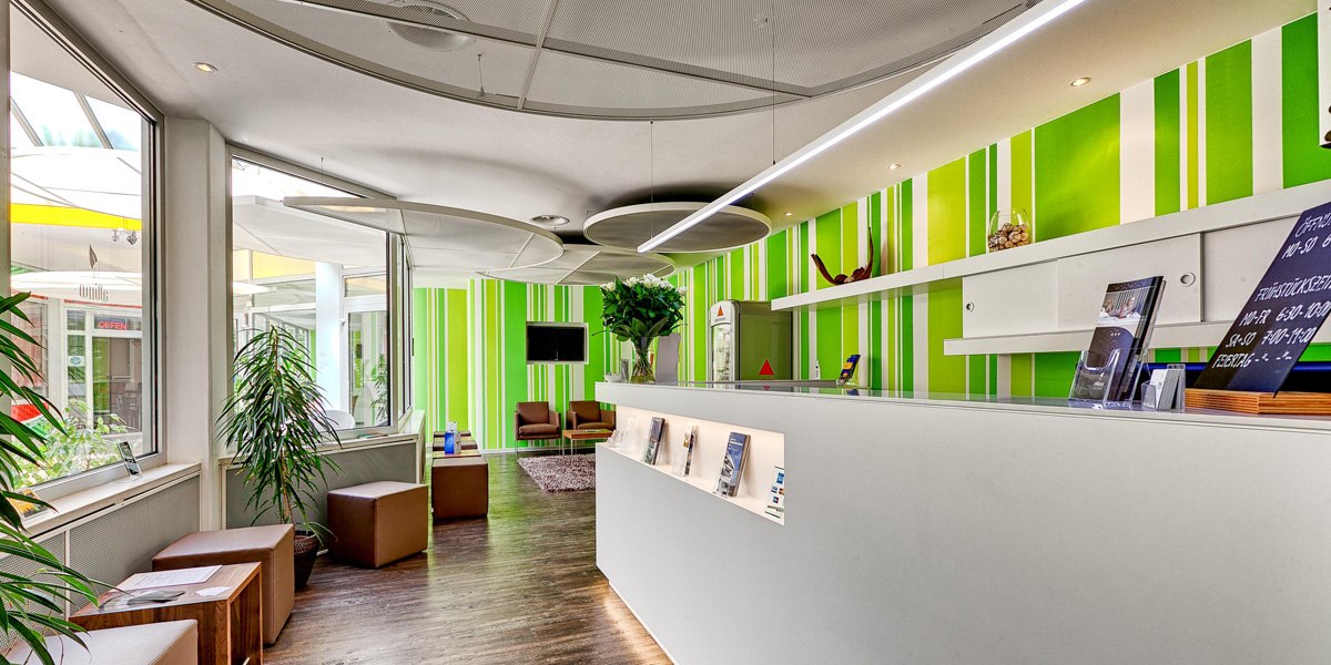 Modern reception with green and white striped wall, plants and seating area. Bright, inviting atmosphere with brochures and decoration., &copy; attimo