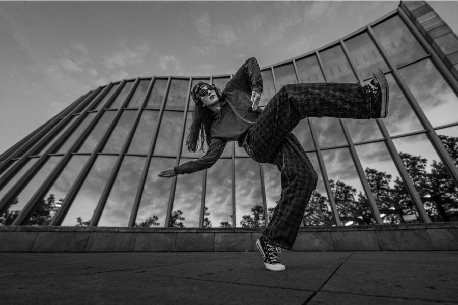 Frau tanzt in dynamischer Pose vor einem modernen Gebäude mit Glasfassade. Schwarz-weiß-Fotografie, dramatische Perspektive., © Fotocredit Theater La Lune Stuttgart