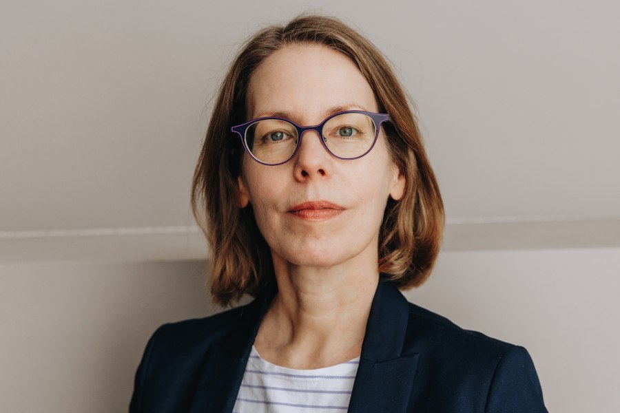 Frau mit Brille und braunen Haaren trägt einen Blazer und ein gestreiftes Shirt. Sie blickt direkt in die Kamera vor neutralem Hintergrund., © Foto: Finanzwende Felix Brüggemann