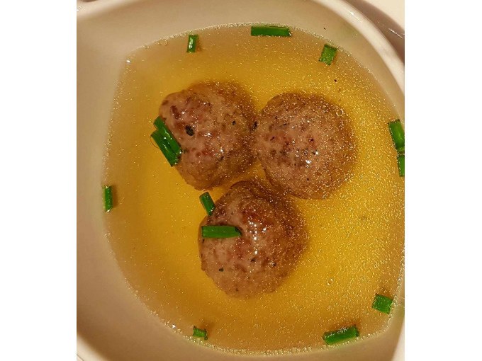Drei Fleischbällchen schwimmen in klarer Brühe, garniert mit Schnittlauch, in einer weißen Schüssel., © Kultweine-Kochwelten-Kunstücke - Kochschule Sonja Lenz Drei Fleischbällchen schwimmen in klarer Brühe, garniert mit Schnittlauch, in einer weißen Schüssel., © Kultweine-Kochwelten-Kunstücke - Kochschule Sonja Lenz