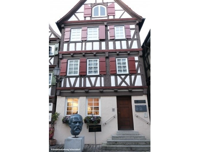 Fachwerkhaus in Schorndorf mit einer Büste von Gottlieb Daimler vor dem Eingang. Das Gebäude hat rote Fensterläden und eine Treppe führt zur Tür., © Eigenbetrieb Tourismus und Citymanagement Schorndorf Fachwerkhaus in Schorndorf mit einer Büste von Gottlieb Daimler vor dem Eingang. Das Gebäude hat rote Fensterläden und eine Treppe führt zur Tür., © Eigenbetrieb Tourismus und Citymanagement Schorndorf