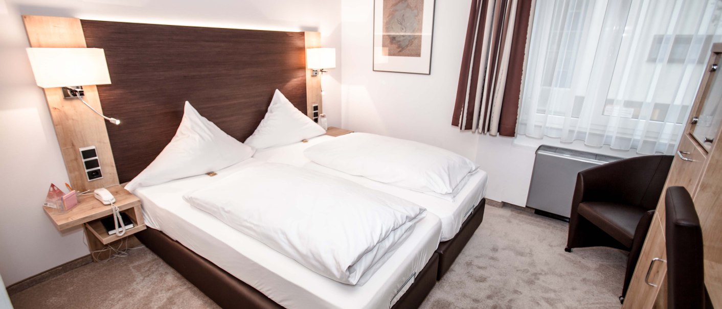 Modern hotel room with double bed, white comforters, bedside tables, lamps, an armchair and a large window with curtains., © Hotel Gasthof Hasen Modern hotel room with double bed, white comforters, bedside tables, lamps, an armchair and a large window with curtains., © Hotel Gasthof Hasen