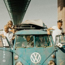 Gruppe in einem blauen VW-Bus unter einer Brücke. Der Bus ist alt und rostig. Die Personen schauen fröhlich aus den Fenstern., © links im Bild Gruppe in einem blauen VW-Bus unter einer Brücke. Der Bus ist alt und rostig. Die Personen schauen fröhlich aus den Fenstern., © links im Bild