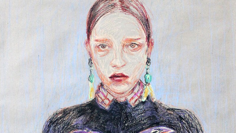 Ein ausdrucksstarkes Porträt einer Frau mit ernster Miene, bunten Ohrringen und einem dunklen Oberteil mit auffälligem Schriftzug., © Württembergische Staatstheater Stuttgart Ein ausdrucksstarkes Porträt einer Frau mit ernster Miene, bunten Ohrringen und einem dunklen Oberteil mit auffälligem Schriftzug., © Württembergische Staatstheater Stuttgart