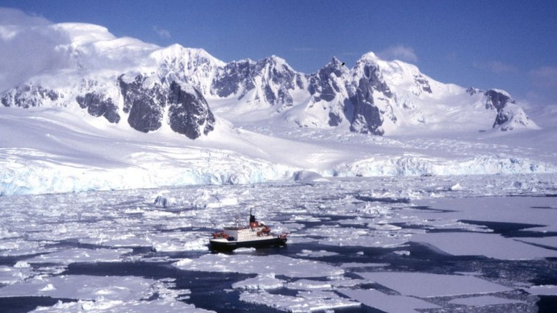 Ein Schiff f&auml;hrt durch das Eis in der Antarktis, umgeben von schneebedeckten Bergen und einer eisigen Landschaft., &copy; Bluemel