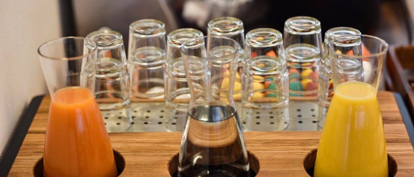 Three carafes with juice and water on a wooden tray, surrounded by upturned glasses., &copy; TOMAS