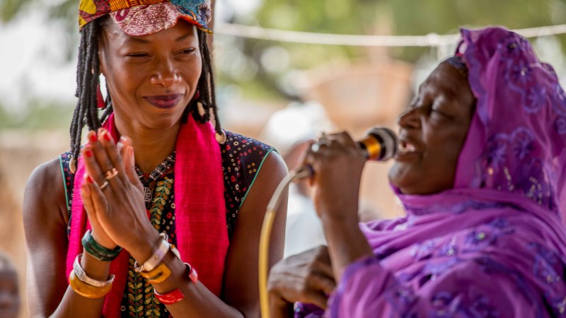 Zwei Frauen, eine klatscht, die andere singt in ein Mikrofon, beide in bunter Kleidung., © Beetz Brothers Zwei Frauen, eine klatscht, die andere singt in ein Mikrofon, beide in bunter Kleidung., © Beetz Brothers