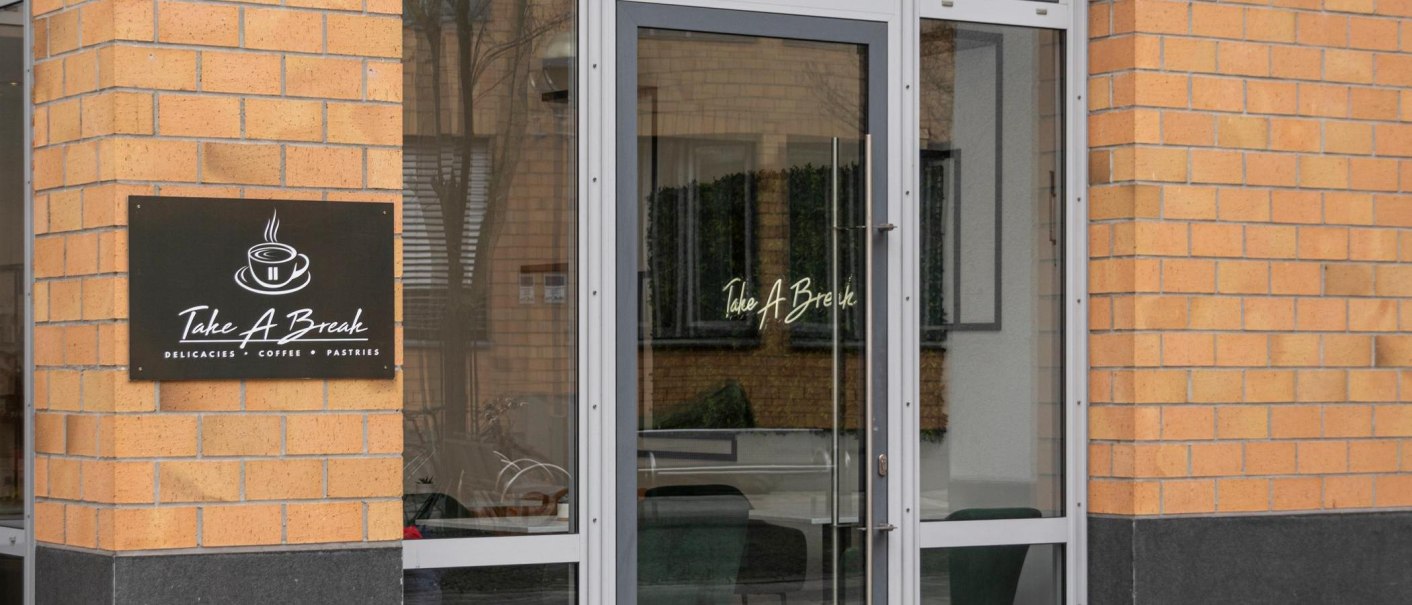 Entrance to the café called 'Take A Break'. A sign shows a cup of coffee and the words 'Delicacies, Coffee, Pastries'., © Stuttgart-Marketing GmbH, Sarah Schmid Entrance to the café called 'Take A Break'. A sign shows a cup of coffee and the words 'Delicacies, Coffee, Pastries'., © Stuttgart-Marketing GmbH, Sarah Schmid