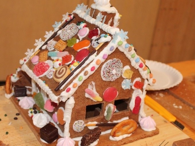 A lovingly decorated gingerbread house with colorful sweets and icing on a wooden table., © Cool-Tours StattReisen A lovingly decorated gingerbread house with colorful sweets and icing on a wooden table., © Cool-Tours StattReisen